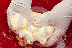 Gloved hands kneading the dough. Making delicious and traditional Brazilian Cheese Bread Pao de Queijo.