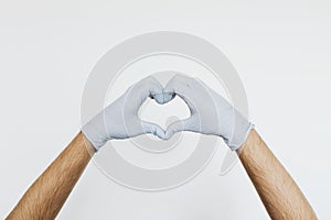 Gloved hands making a heart shaped sign on a gray background