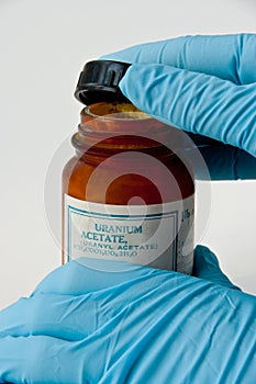 Gloved hands opening a bottle of uranium acetate photo