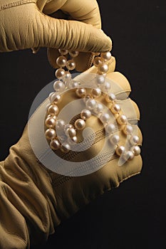 Gloved hands playing with a string of pearls