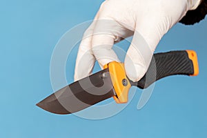 A gloved man carefully holds a knife as evidence of a crime. Knife in the hand of an expert, forensic scientist