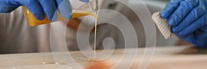 Gloved man pours yellow liquid tree, woodworking