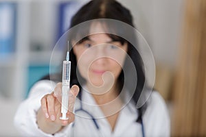 gloved mature doctor in whitecoat holding syringe before making injection