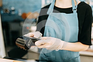 A gloved waiter with a cashless payment terminal