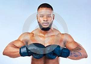 Gloves, boxing and portrait of a serious black man isolated on a blue background in studio. Ready, fitness and an