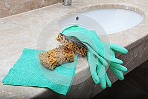 Gloves and a cleaning sponge lie on the marble sink in the bathroom. The view from the top. Items of sanitary hygiene and