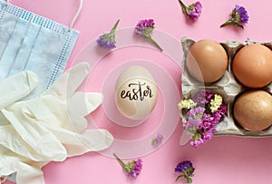 Gloves, facemask, flowers and eggs with inscription EASTER over pink background