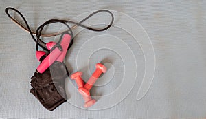 Gloves ready to training at home, making exercise in a fitness class with muscular equipment. Jumping rope, Pink dumbbells and