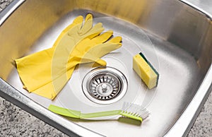 Gloves, sponge and brush in a clean kitchen sink