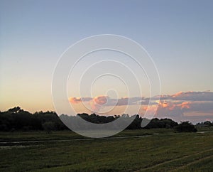 GLOW ON DISTANT CLOUDS AT SUNSET WITH RIVER IN FOREGROUND IN AFRICA