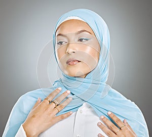 A glowing beautiful muslim woman isolated against grey copyspace background. Young woman wearing a hijab or headscarf