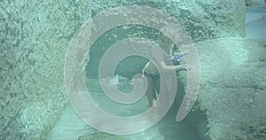 Glowing blue spots of light against caucasian girl walking close to the rocks near the sea