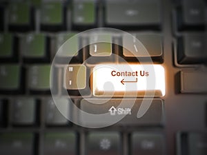 A glowing bright `contact us` button, key, message on the keyboard. Customer service concept. Internet or online contact for