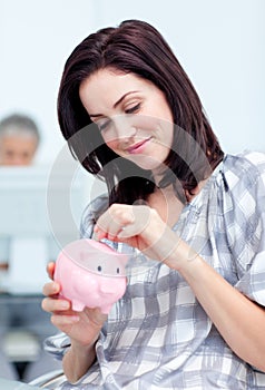 Glowing businesswoman saving money in a piggy-bank