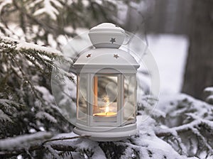 Glowing candle in lantern hanging on fir tree branch in winter forest. Christmas scene