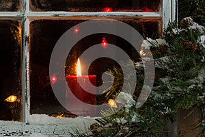 Glowing Christmas candle in frosted home window