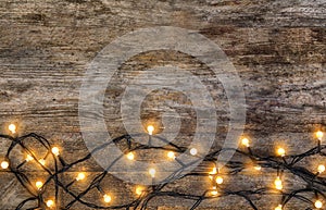 Glowing Christmas lights on wooden background