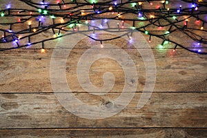 Glowing Christmas lights on wooden background, top view