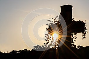 Glowing cross silhouette with sunbeams sunset sunlight and clear evening sky shows christianity spirituality of church and forgive