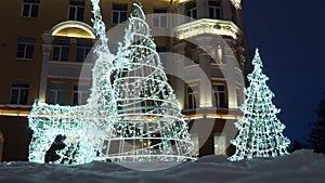 Glowing deer and christmas tree. Festive New Year Christmas electrical art installation, architecture structure in