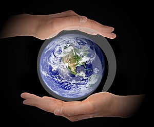 Glowing earth globe in hands on black background, environment concept, elements of this image furnished by NASA