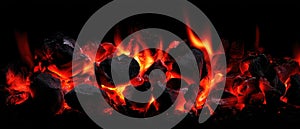 The glowing embers of a charcoal fire casting warm light in darkness. AI generated image