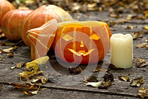 Glowing evil Halloween pumpkin on wooden old floor with dry autumn leaves