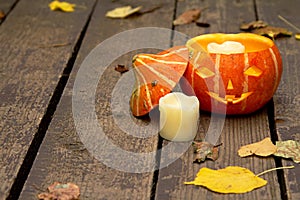 Glowing evil Halloween pumpkin on wooden old floor with dry autumn leaves