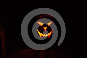 Glowing fiery Jack-o`-lantern face from a pumpkin with candle on a halloween
