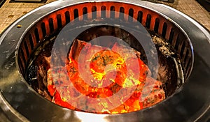 Glowing and flaming hot natural wood charcoal in BBQ grill stove background