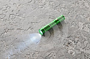 A glowing flashlight on a gray concrete table