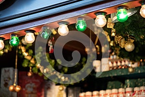 Glowing glass bulb garland of shiny Christmas lights at blurry background. New Year illuminations. Green and golden retro lamps