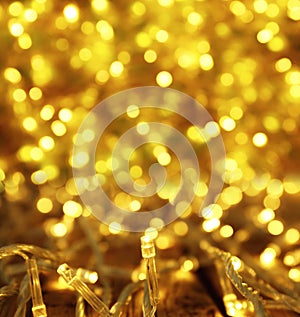 Glowing gold Christmas lights on table, closeup. Bokeh effect