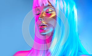 Glowing gold skin. Fashion model woman face in bright neon colourful lights, beautiful sexy woman with white hair and trendy make-
