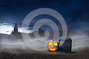 Glowing halloween pumpkin beside grave stones