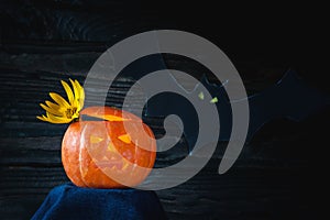 Glowing Halloween pumpkin with yellow flower in the shape of a crown on a dark background.