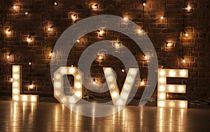 Glowing letters of love against a backdrop of lights and brick walls