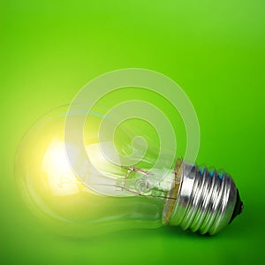 Glowing light bulb over green background