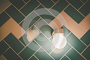 Glowing light bulb on tiled bathroom wall.