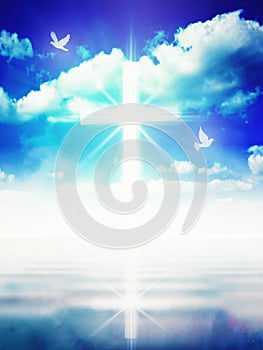 Glowing light Christian cross on blue sky, white doves, water mirror reflection