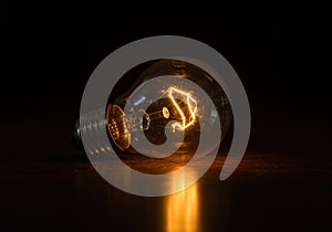 A glowing lightbulb on a dark surface, emitting a warm and inviting light.