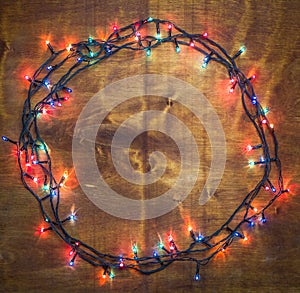 Glowing lights for Xmas Holiday rounded on wooden background