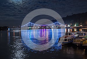 Glowing multicoloured city bridge above river at night