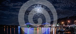 Glowing multicoloured city bridge above river at night