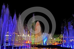 A glowing musical fountain at night. Splashes of colored water