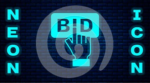Glowing neon Bid icon isolated on brick wall background. Auction bidding. Sale and buyers. Vector