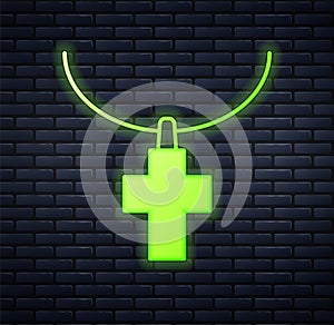 Glowing neon Christian cross on chain icon isolated on brick wall background. Church cross. Vector