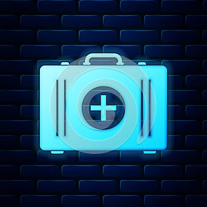 Glowing neon First aid kit icon isolated on brick wall background. Medical box with cross. Medical equipment for