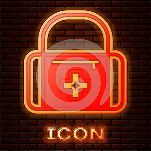 Glowing neon First aid kit icon isolated on brick wall background. Medical box with cross. Medical equipment for
