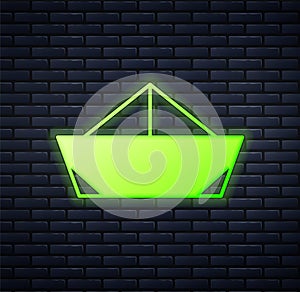 Glowing neon Folded paper boat icon isolated on brick wall background. Origami paper ship. Vector